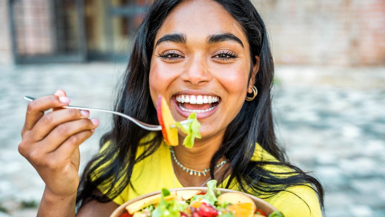 the woman smiles as she eats the salad